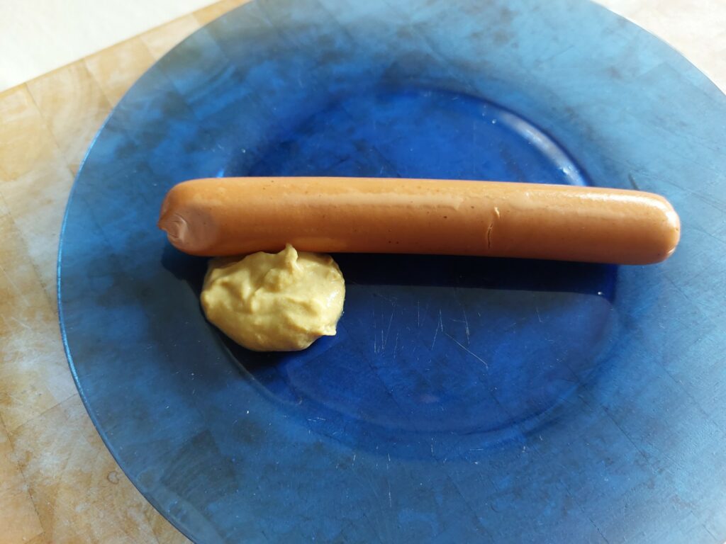 Vegetarische Wiener auf blauem Teller mit Senf