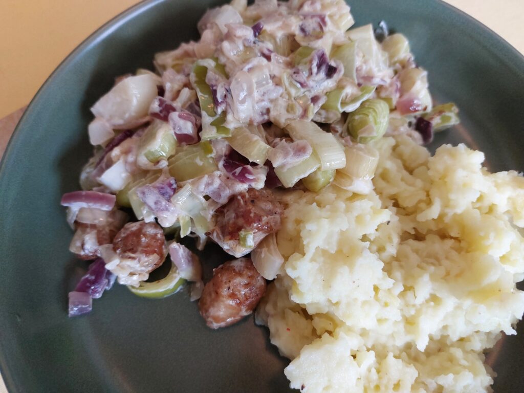 Lauch mit Bratwurst, Zwiebeln und Schmand an Quetschkartoffeln