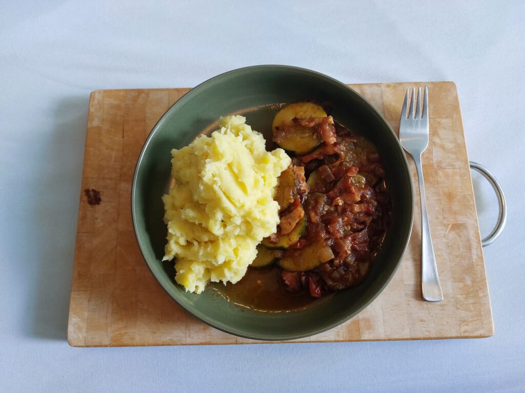 Schmorgurken mit Tomaten und einer Zwiebel-Speck-Basis, dazu Kartoffelbrei