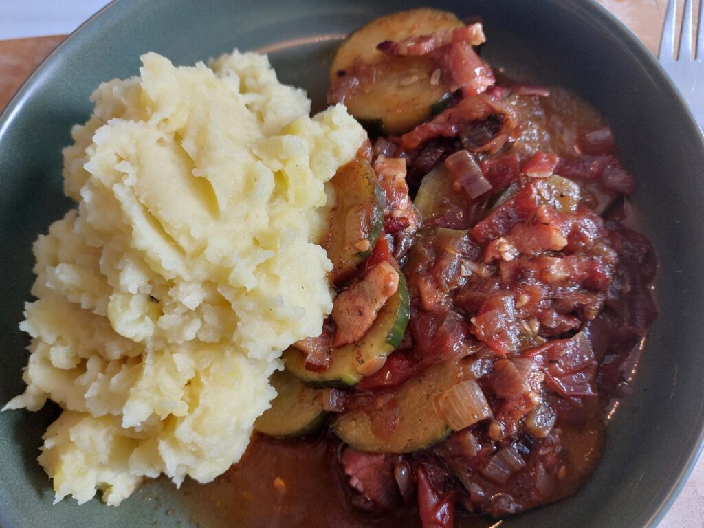 Schmorgurken mit Tomaten und einer Zwiebel-Speck-Basis, dazu Kartoffelbrei