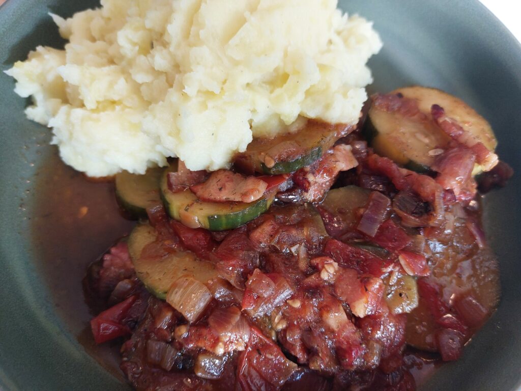 Schmorgurken mit Tomaten und einer Zwiebel-Speck-Basis, dazu Kartoffelbrei