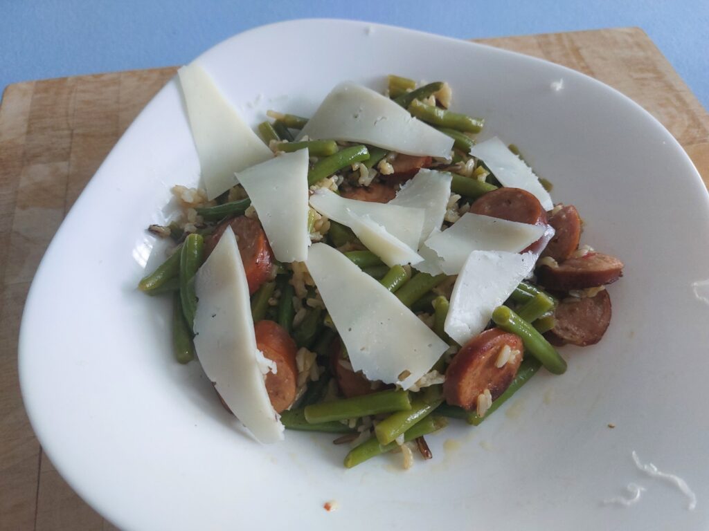 Wurst, Bohnen, Reis, Pfanne mit Ziegenhartkäse, gehobelt